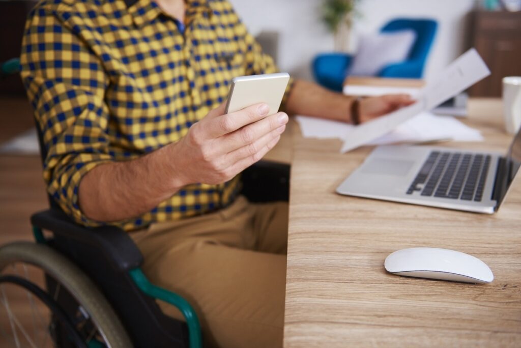 personne en fauteuil roulant qui travail avec des outils numériques