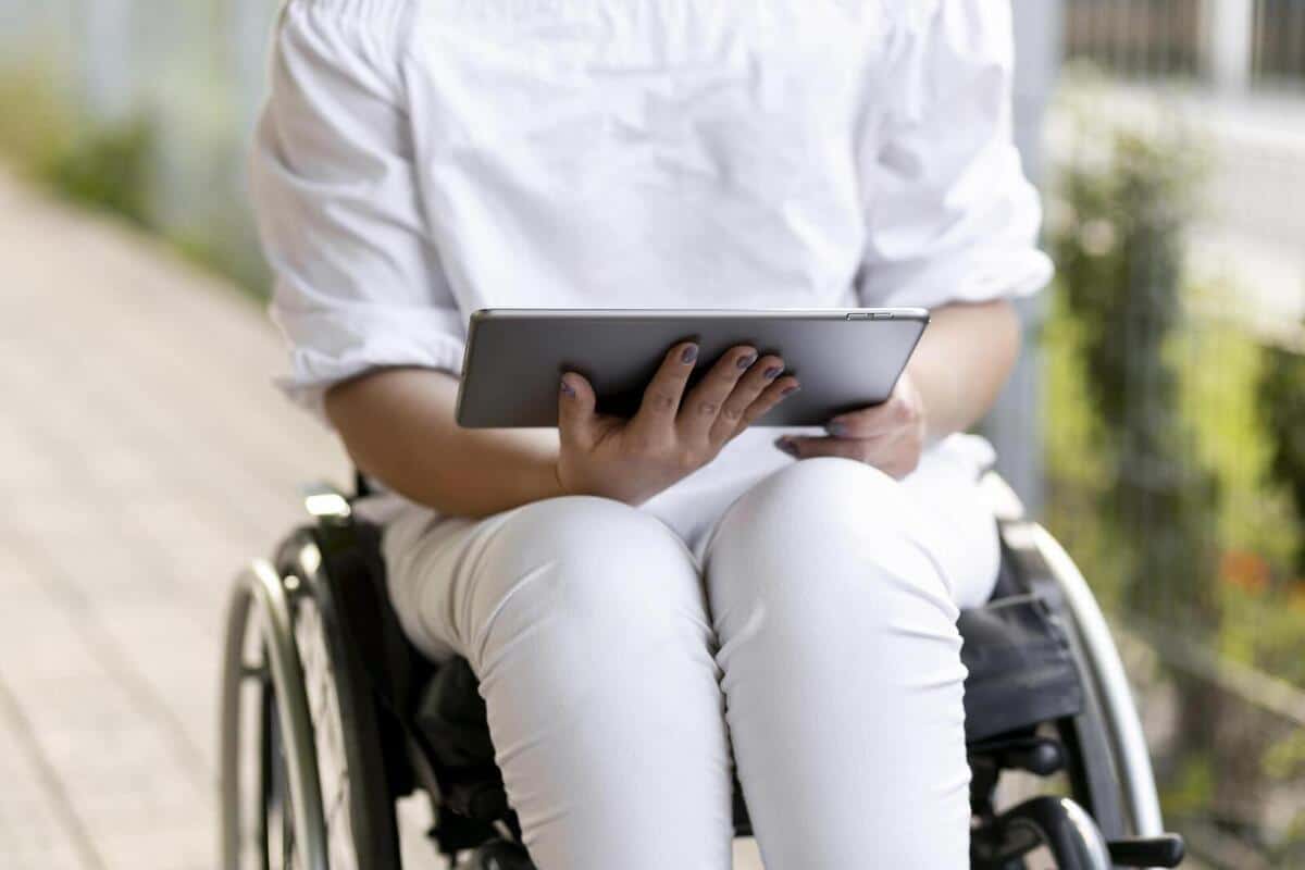 photo d'une personne en fauteuil roulant qui tient une tablette dans ses mains